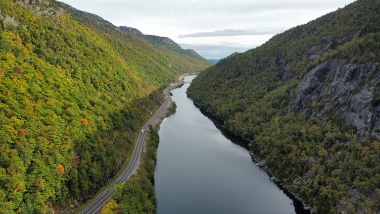 Landscape view of a Valley with a road running through it next to a river, between two mountains.